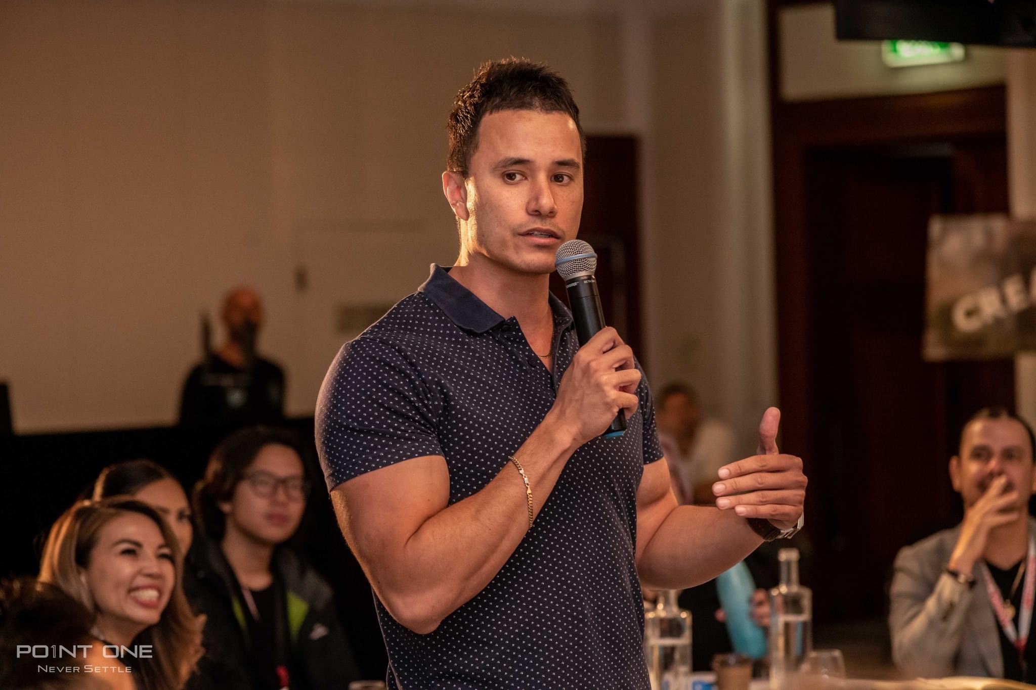 Casey Barnard holding a microphone while speaking at an event